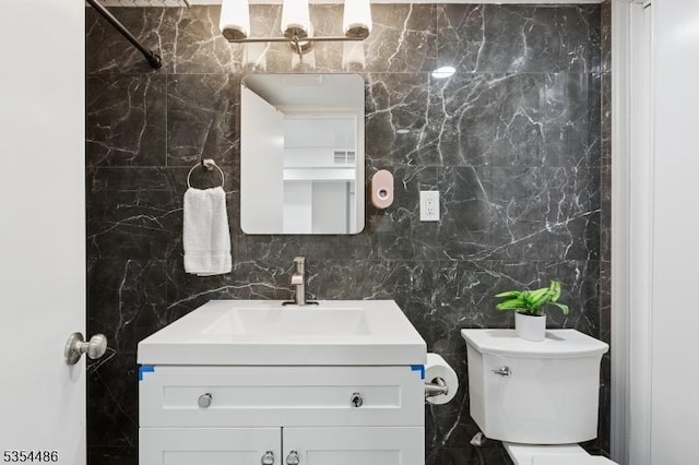 bathroom with tile walls, vanity, and toilet