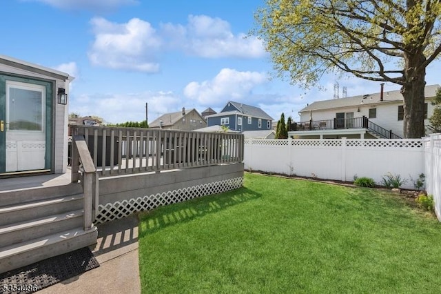 view of yard featuring a residential view, a wooden deck, and a fenced backyard
