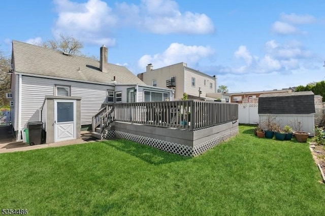 back of house with a wooden deck, a shed, an outbuilding, a chimney, and a lawn