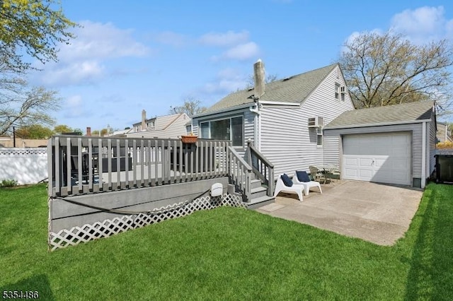 back of house with a lawn, a wooden deck, concrete driveway, and roof with shingles