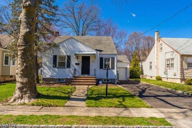 bungalow-style home featuring a detached garage, an outdoor structure, and a front lawn