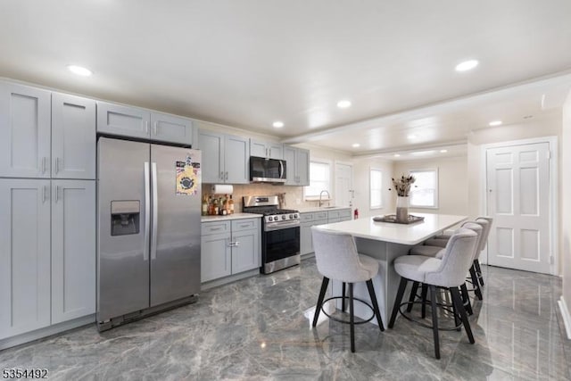 kitchen with a breakfast bar, light countertops, stainless steel appliances, recessed lighting, and a kitchen island