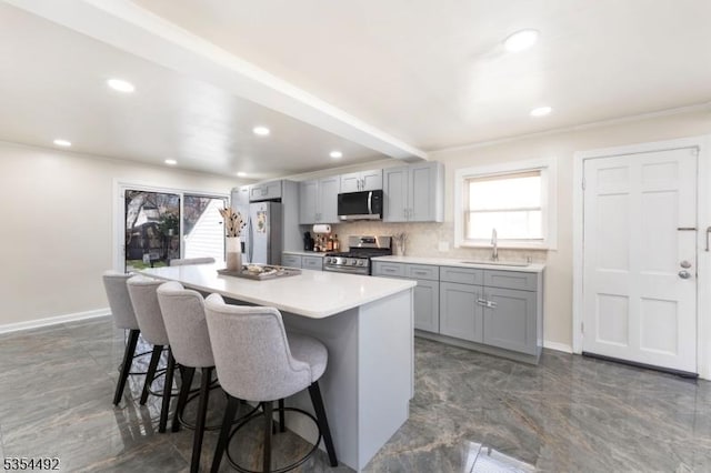 kitchen featuring a sink, gray cabinets, a breakfast bar, and stainless steel appliances