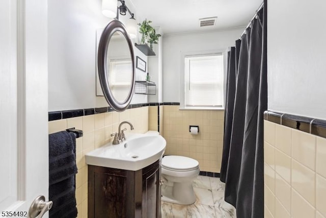 bathroom with visible vents, vanity, marble finish floor, toilet, and tile walls