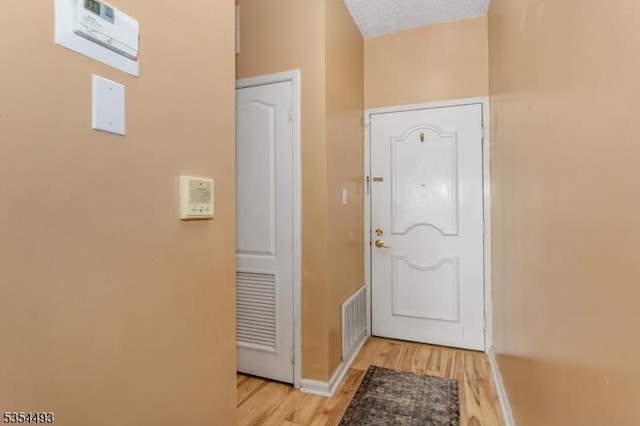 doorway with baseboards, visible vents, and light wood-type flooring