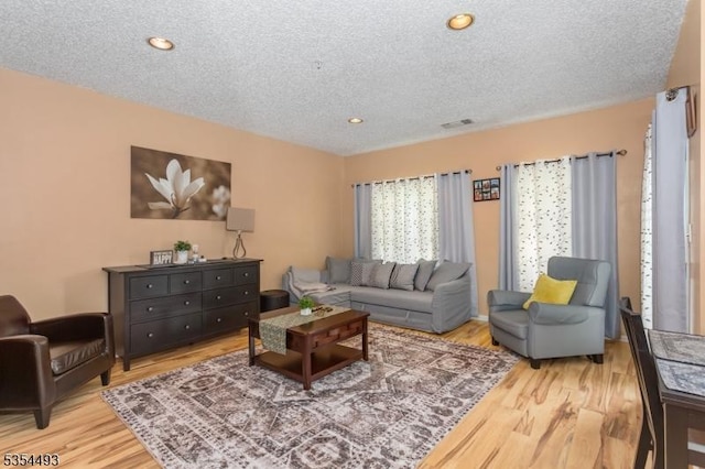 living area with visible vents, a textured ceiling, and wood finished floors