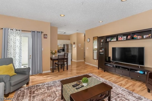 living room with recessed lighting, a textured ceiling, baseboards, and light wood-style floors