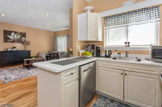 kitchen featuring light wood-style floors, light countertops, stainless steel appliances, and a peninsula