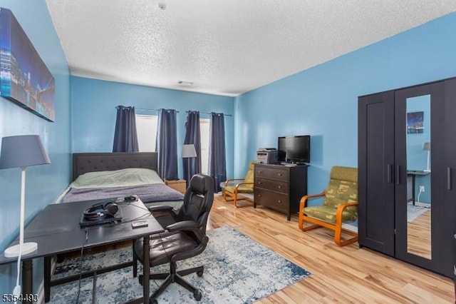 bedroom with a textured ceiling and wood finished floors
