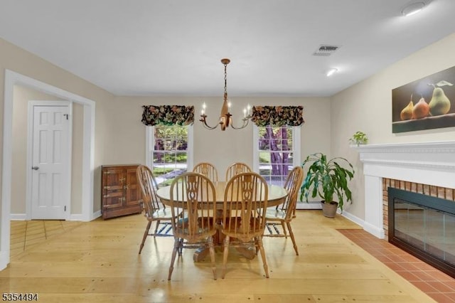 21 Dorset Rd, Washington Twp, NJ 07853 - dining area with a chandelier, light wood-type flooring, baseboards, and a brick fireplace