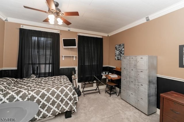 bedroom with a wainscoted wall, ornamental molding, ceiling fan, and light colored carpet