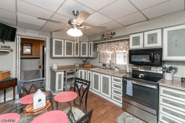 kitchen with ceiling fan, black microwave, a sink, electric stove, and a drop ceiling