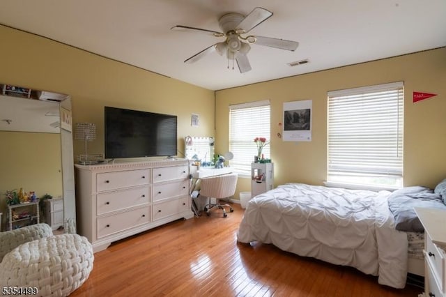 bedroom featuring light wood-type flooring, ceiling fan, and visible vents