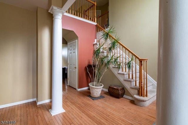 stairs featuring arched walkways, baseboards, decorative columns, and hardwood / wood-style flooring