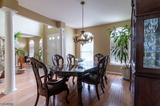 dining area featuring a notable chandelier, decorative columns, baseboards, and light wood-style floors