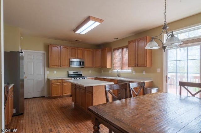 kitchen featuring a kitchen island, light countertops, dark wood finished floors, hanging light fixtures, and stainless steel appliances
