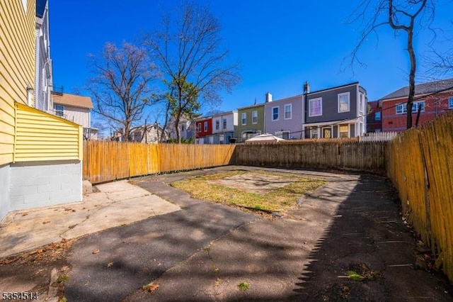 view of yard with a residential view, a fenced backyard, and a patio area