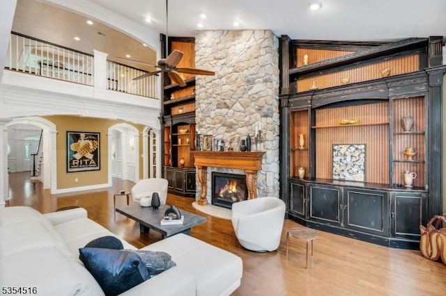 26 Avon Rd, Warren Twp, NJ 07059 - living room with arched walkways, a ceiling fan, a high ceiling, a fireplace, and wood finished floors