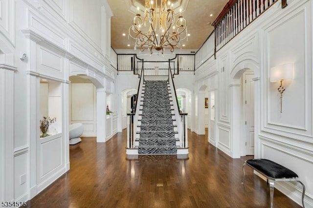 26 Avon Rd, Warren Twp, NJ 07059 - foyer entrance with a decorative wall, arched walkways, a high ceiling, dark wood finished floors, and stairs