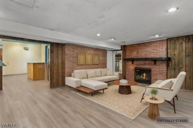 living area with a brick fireplace, wooden walls, recessed lighting, and wood finished floors