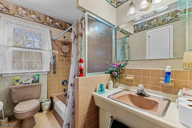 bathroom with a sink, toilet, and tile walls