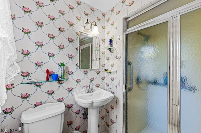 full bathroom featuring toilet, wallpapered walls, and a shower stall