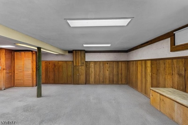 finished basement featuring wood walls and light carpet