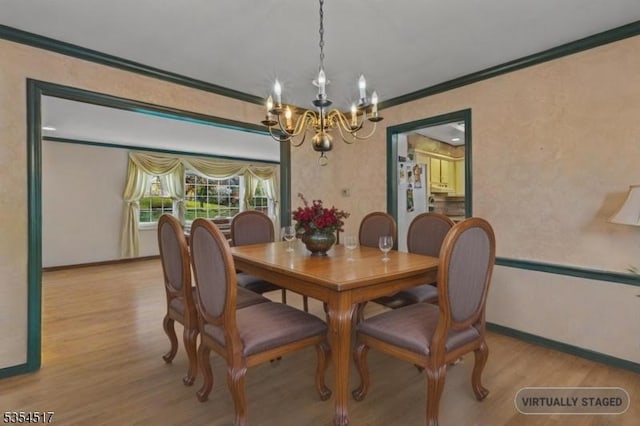dining space featuring crown molding, baseboards, an inviting chandelier, and wood finished floors