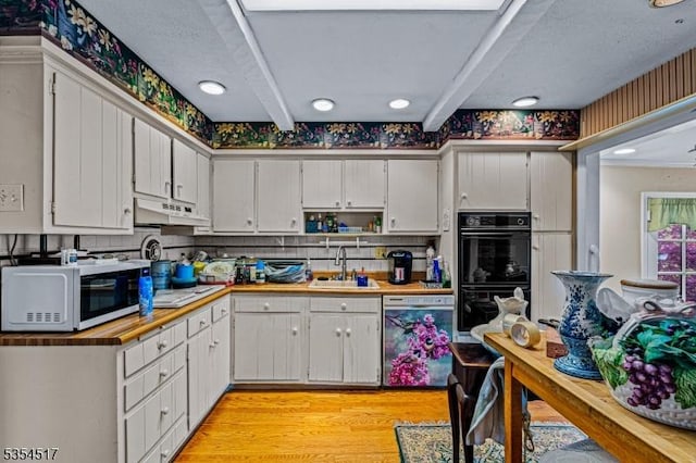 kitchen with dobule oven black, under cabinet range hood, a sink, light wood-style flooring, and dishwasher