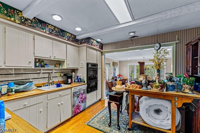 kitchen with open shelves, dishwasher, a sink, light countertops, and light wood finished floors