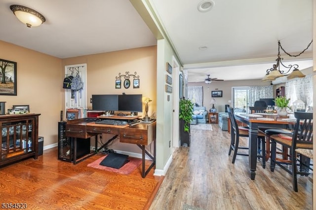 interior space with baseboards, a ceiling fan, and wood finished floors