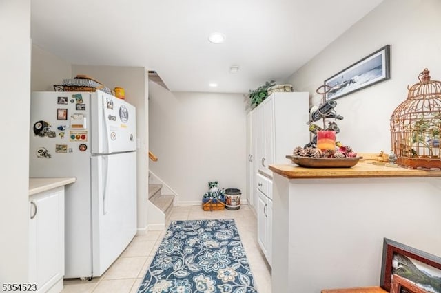 kitchen featuring freestanding refrigerator, light tile patterned flooring, white cabinets, and recessed lighting