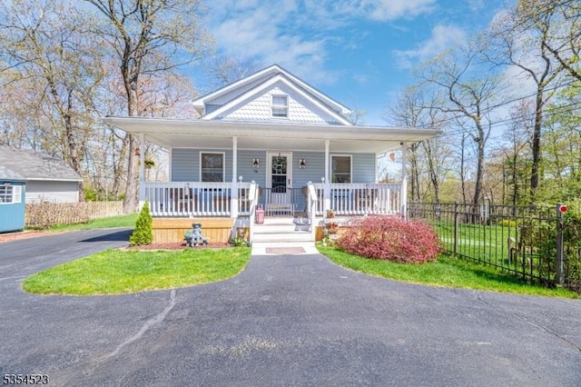 bungalow-style house featuring fence, a porch, and aphalt driveway