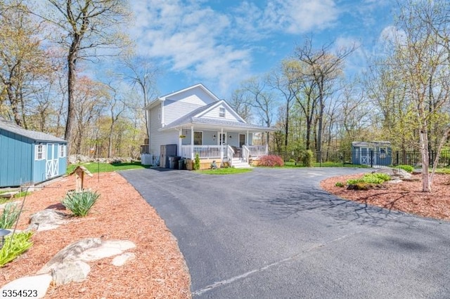 view of front of property with an outbuilding, aphalt driveway, a shed, and covered porch