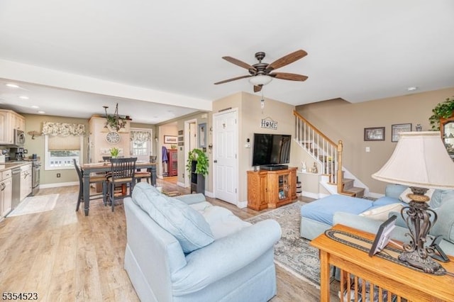 living area featuring stairs, baseboards, ceiling fan, light wood-type flooring, and recessed lighting