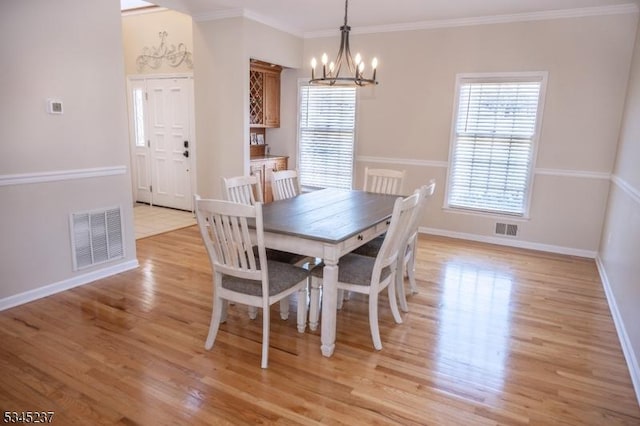 dining space with visible vents, light wood-type flooring, baseboards, and an inviting chandelier