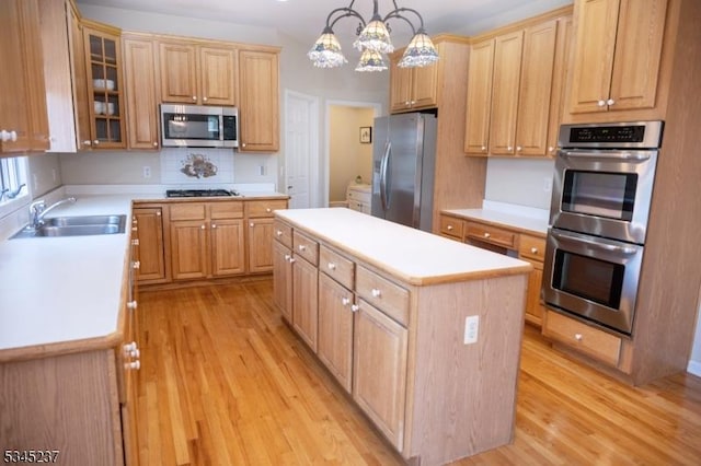 kitchen featuring a sink, appliances with stainless steel finishes, light wood-style floors, and a kitchen island