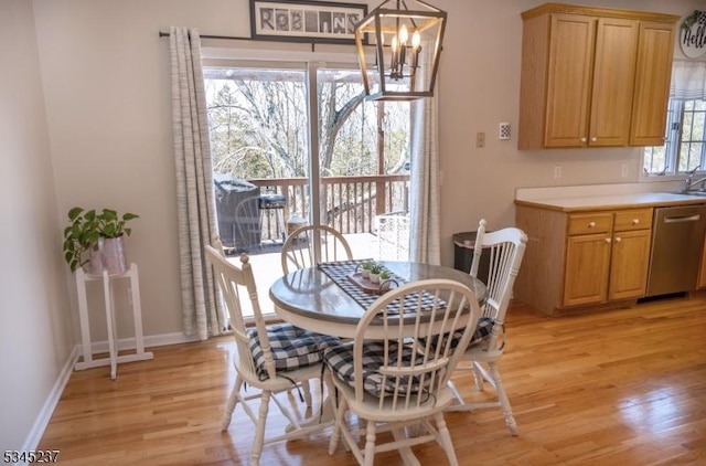 dining space with baseboards, a notable chandelier, and light wood-type flooring