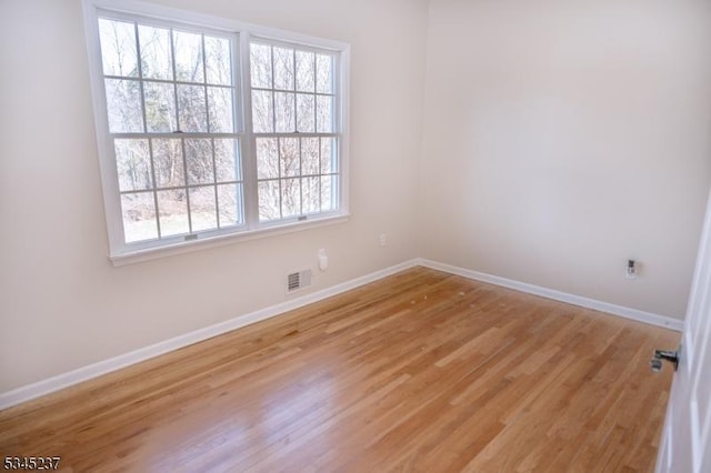 spare room featuring baseboards, visible vents, and light wood finished floors