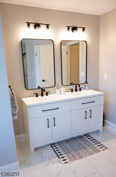 bathroom featuring a sink, baseboards, double vanity, and marble finish floor