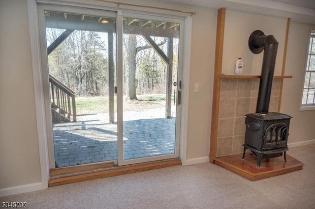 doorway featuring baseboards, a wood stove, and carpet