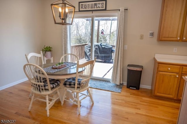 dining room featuring baseboards, a notable chandelier, and light wood finished floors