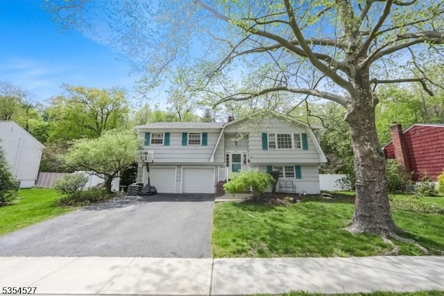 bi-level home featuring fence, an attached garage, driveway, and a front lawn