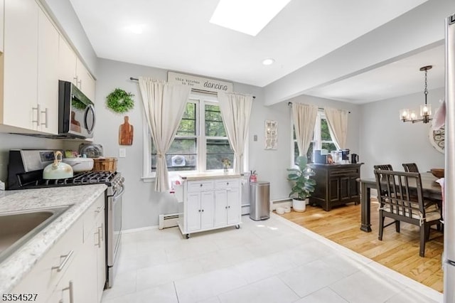 kitchen featuring stainless steel appliances, an inviting chandelier, a healthy amount of sunlight, and baseboard heating