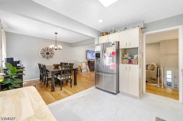kitchen with an inviting chandelier, stainless steel refrigerator with ice dispenser, recessed lighting, white cabinets, and hanging light fixtures
