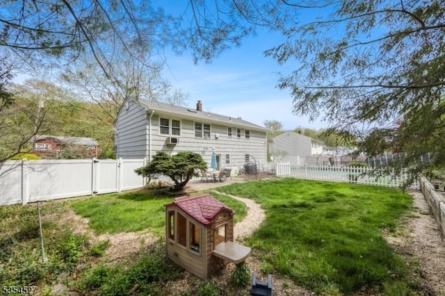 back of house with a fenced backyard, a chimney, a gate, a patio area, and a lawn