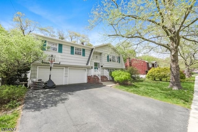 raised ranch featuring a garage, aphalt driveway, and a gambrel roof
