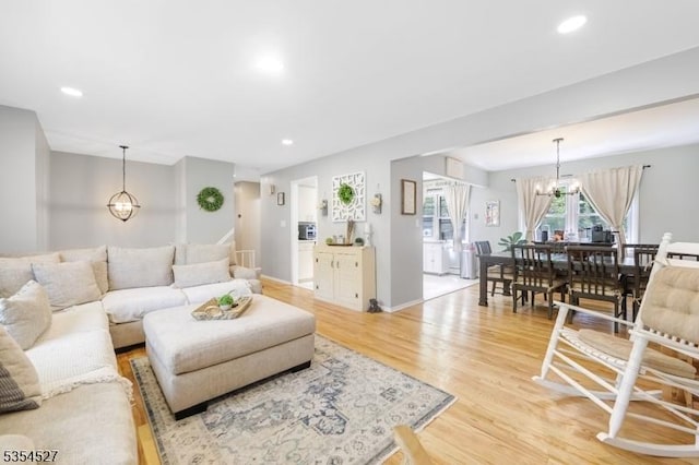 living area featuring recessed lighting, light wood finished floors, baseboards, and a notable chandelier