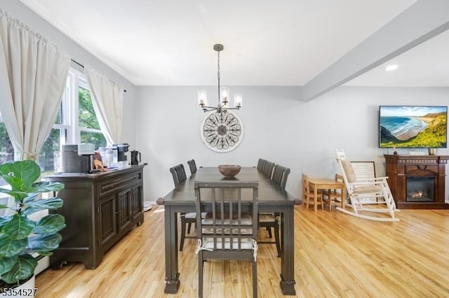dining room featuring an inviting chandelier, a glass covered fireplace, recessed lighting, and light wood-style flooring