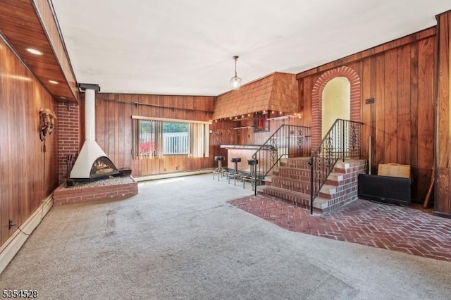 226 Wilson Rd, Franklin Twp, NJ 08873 - carpeted living room featuring wooden walls, a baseboard radiator, and a wood stove